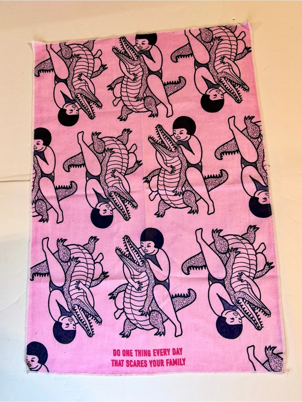 Funny pink dish / tea towel with a repeating print of a person wrestling an alli